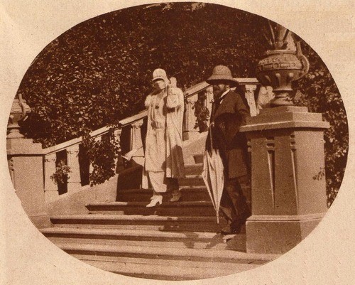 Photographie en noir et blanc de la reine Élisabeth de Belgique, vêtue d'une robe claire et coiffée d'un chapeau, descendant les escaliers du Winter Palace Hotel à Louxor en Égypte, en février 1923, accompagnée  de l'égyptologue belge Jean Capart, avant leur visite officielle du tombeau de Toutankhamon.