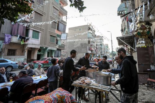 Jeûneurs assis en silence autour d'une longue table d'Iftar collectif, attendant le coucher du soleil pour rompre le jeûne tous ensemble durant le Ramadan en Egypte