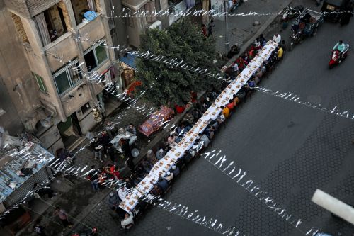 Grande table d'Iftar organisée par une entreprise ou une association de bienfaisance, avec des bénévoles servant les convives durant le Ramadan en Egypte