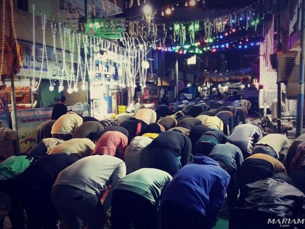 Foule de fidèles alignés pour la prière nocturne du Tarawih dans une rue égyptienne, les tapis s'étendant loin devant une mosquée bondée pendant le Ramadan en Egypte