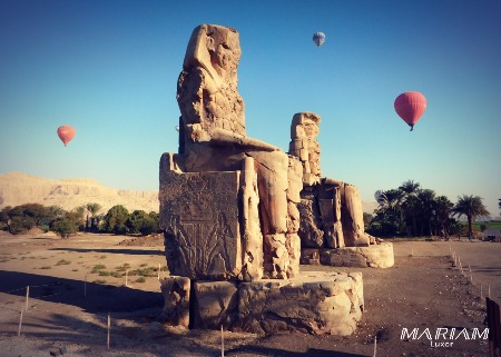 Colosses de Memnon au lever du soleil avec des montgolfières survolant la rive ouest de Louxor