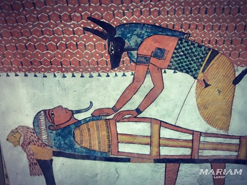 Relief funéraire de la tombe de Sennedjem (TT1) à Deir el-Médineh représentant le dieu Anubis, à tête de chacal, se penchant sur la momie d'Osiris-Sennedjem allongée sur un lit léonine, lors du rituel de momification.
