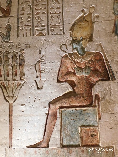 Relief du temple ptolémaïque d'Hathor à Deir el-Médineh représentant le dieu Osiris assis sur son trône, juge suprême des morts, figuré sous les traits d'une momie royale, coiffé de la couronne Atef et tenant les insignes de l'autorité, le crochet et le fléau . La scène est située dans une chapelle  du sanctuaire, un espace dédié aux rites osiriens et à la renaissance du dieu, en lien avec le contexte funéraire de la nécropole thébaine