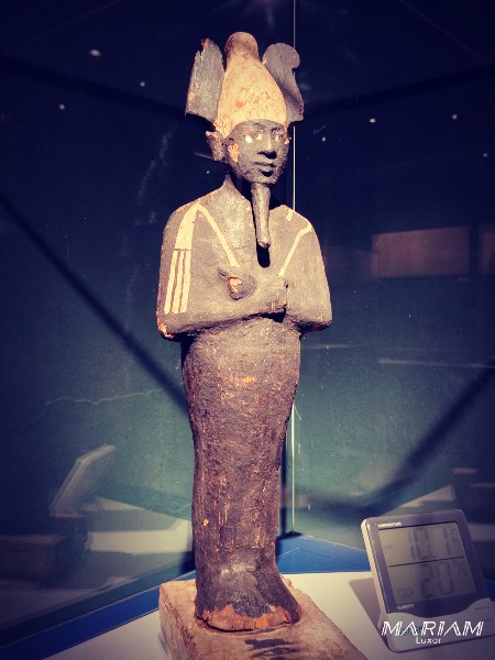 Statue en bois peint en noir représentant le dieu Osiris, momiforme, coiffé de la couronne Atef, tenant le crochet et le fléau, conservée au Musée de la Momification de Louxor.