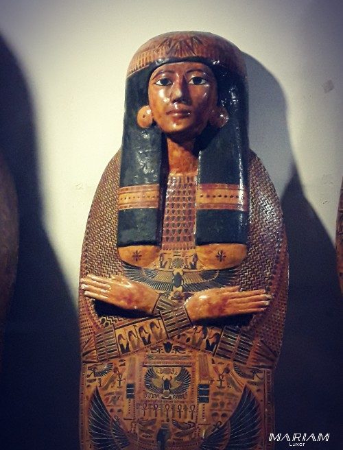 Photographie d'un cartonnage de momie de la Troisième Période intermédiaire, exposé au Musée de Louxor, en forme d'enveloppe anthropomorphe décorée de scènes peintes et de hiéroglyphes.